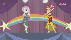 Size: 1136x638 | Tagged: safe, imported from derpibooru, screencap, fluttershy, sunset shimmer, dance magic, equestria girls, spoiler:eqg specials, alternate hairstyle, awkward smile, ballet slippers, canterlot high, clothes, dress, duo, female, flamenco dress, high heels, rainbow, shoes, skirt, smiling, stars, sunset shimmer flamenco dress, teletoon, tutu