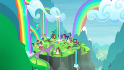 Size: 1440x810 | Tagged: safe, imported from derpibooru, screencap, trade ya, background, bridge, cliff, cloud, liquid rainbow, mountain, no pony, rainbow, rainbow falls (location), rainbow waterfall, scenery, town, train tracks, valley