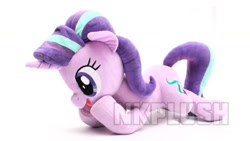 Size: 1280x720 | Tagged: safe, alternate version, artist:nekokevin, imported from derpibooru, starlight glimmer, pony, unicorn, series:nekokevin's glimmy, female, irl, lying down, mare, obtrusive watermark, open mouth, photo, plushie, raised hoof, simple background, smiling, solo, watermark, white background