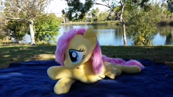 Size: 3264x1836 | Tagged: safe, artist:joltage, imported from derpibooru, fluttershy, pegasus, pony, blanket, crossed legs, female, irl, lake, lying down, outdoors, photo, plushie, solo