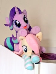 Size: 768x1024 | Tagged: safe, artist:nekokevin, imported from derpibooru, fluttershy, starlight glimmer, pegasus, pony, unicorn, series:nekokevin's glimmy, clothes, duo, female, irl, lying down, mare, on top, open mouth, photo, plushie, smiling, socks, striped socks, underhoof