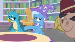 Size: 1920x1080 | Tagged: safe, imported from derpibooru, screencap, gallus, grampa gruff, trixie, griffon, pony, unicorn, a horse shoe-in, bookshelf, cape, clothes, couch, female, hat, male, mare, quadrupedal, trixie's cape, trixie's hat