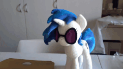 Size: 800x450 | Tagged: safe, artist:nekokevin, imported from derpibooru, dj pon-3, vinyl scratch, human, pony, unicorn, animated, chair, female, gif, grabbing, hand, irl, irl human, magnet, mare, offscreen character, photo, plushie, smiling, solo focus, sunglasses, table