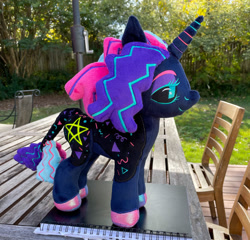 Size: 1280x1227 | Tagged: safe, artist:whalephooey, imported from derpibooru, oc, oc only, oc:twinkle pop, pony, unicorn, black sclera, book, chair, commission, horn, irl, outdoors, photo, plushie, pony plushie, smiling, table, unicorn oc