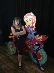 Size: 1200x1598 | Tagged: safe, imported from derpibooru, sunset shimmer, human, equestria girls, friendship games, boots, cardboard cutout, clothes, gloves, high heels, irl, irl human, motorcross, photo, rebecca shoichet, rebecca shoichet with cardboard cutout, shoes, voice actor