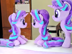 Size: 1024x768 | Tagged: safe, artist:nekokevin, imported from derpibooru, imported from ponybooru, starlight glimmer, pony, unicorn, series:nekokevin's glimmy, female, irl, mare, multeity, photo, plushie, self ponidox, similo duplexis, sitting, size difference, smiling, starlight cluster, table, trio, underhoof