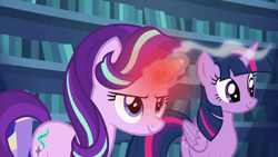 Size: 1000x562 | Tagged: safe, imported from derpibooru, screencap, starlight glimmer, twilight sparkle, alicorn, pony, unicorn, every little thing she does, duo, duo female, female, glowing horn, happy, horn, indoors, library, looking ahead, looking forward, looking up, magic, magic aura, overheated horn, smiling, smoke, twilight sparkle (alicorn), twilight's castle
