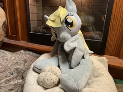 Size: 4032x3024 | Tagged: safe, artist:ciaran, imported from derpibooru, derpy hooves, bed, female, fireplace, food, grooming, irl, looking at you, muffin, photo, photography, plushie, preening, rug, welovefine