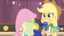 Size: 3410x1920 | Tagged: safe, imported from derpibooru, screencap, applejack, fluttershy, best in show: the pre-show, equestria girls, equestria girls series, spoiler:eqg series (season 2), applejack's hat, belt, best in show logo, clothes, cowboy hat, cute, cutie mark, cutie mark on clothes, denim skirt, female, geode of super strength, grin, hat, jackabetes, jewelry, magical geodes, microphone, necklace, skirt, smiling