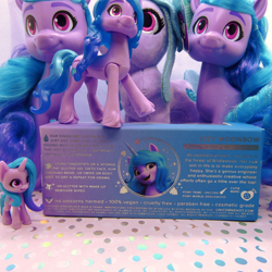 Size: 1158x1159 | Tagged: safe, imported from derpibooru, photographer:g5mlp, photographer:imiya, izzy moonbow, pony, unicorn, brushable, female, g5, izzystorm, mare, merchandise, multeity, my little pony logo, plushie, text, toy, unicorn charms izzy moonbow, unicorn snot