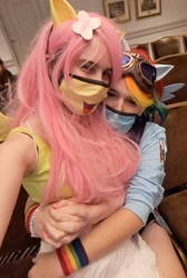 Size: 1377x2048 | Tagged: safe, artist:darknightprincess, artist:magicalmysticva, imported from derpibooru, fluttershy, rainbow dash, human, clothes, convention, cosplay, costume, couple, cute, face mask, female, females only, flutterdash, goggles, holding hands, irl, irl human, lesbian, mask, photo, ponyville ciderfest, shipping, sitting on lap