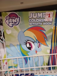 Size: 3000x4000 | Tagged: safe, imported from derpibooru, rainbow dash, pegasus, pony, coloring book, dollar tree, family dollar, female, high res, irl, mare, my little pony jumbo coloring book, my little pony logo, open mouth, open smile, photo, price tag, raised hoof, smiling, solo, spread wings, sticker, wings