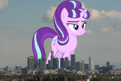 Size: 1023x682 | Tagged: safe, artist:dashiesparkle edit, artist:thegiantponyfan, edit, imported from derpibooru, starlight glimmer, pony, unicorn, california, female, giant pony, giant starlight glimmer, giant unicorn, giantess, highrise ponies, irl, lidded eyes, los angeles, macro, mare, mega giant, multicolored mane, multicolored tail, photo, ponies in real life, s5 starlight, smiling, story included, tail