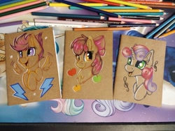 Size: 1152x864 | Tagged: safe, artist:julunis14, imported from derpibooru, apple bloom, scootaloo, sweetie belle, earth pony, pegasus, pony, unicorn, apple, apple bloom's bow, bow, bust, colored pencil drawing, cute, cutie mark crusaders, excited, female, filly, floating wings, foal, food, hair bow, music notes, notebook, open mouth, open smile, smiling, spread wings, traditional art, wings