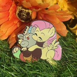 Size: 688x688 | Tagged: safe, artist:3ggmilky, imported from derpibooru, discord, fluttershy, draconequus, pegasus, baby, baby discord, cute, enamel, enamel pin, flower, grass, hug, irl, merchandise, photo, selling