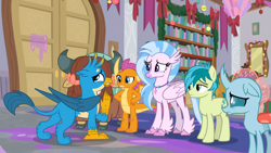 Size: 1600x900 | Tagged: safe, imported from derpibooru, screencap, gallus, ocellus, sandbar, silverstream, smolder, yona, changedling, changeling, classical hippogriff, dragon, earth pony, griffon, hippogriff, pony, yak, the hearth's warming club, bookshelf, bow, cloven hooves, colored hooves, dragoness, female, hair bow, hand on hip, jewelry, male, monkey swings, necklace, student six