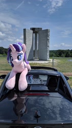 Size: 2160x3840 | Tagged: safe, imported from derpibooru, starlight glimmer, pony, unicorn, car, chain link fence, cloud, elbert county, female, fence, georgia (state), georgia guidestones, granite, grass, irl, lidded eyes, lying down, mare, monument, photo, plushie, prone, solo, tree