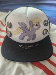 Size: 960x1280 | Tagged: safe, imported from derpibooru, derpy hooves, pegasus, pony, buttons, cap, death metal, hat, irl, merchandise, photo, safety pin, solo