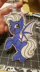 Size: 5312x2988 | Tagged: safe, artist:inkkeystudios, imported from derpibooru, oc, oc only, bat pony, pony, badge, fangs, looking at you, open mouth, open smile, photo, smiling, solo, spread wings, traditional art, wings