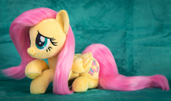 Size: 2182x1288 | Tagged: safe, artist:buttercupbabyppg, imported from derpibooru, fluttershy, pegasus, pony, cute, female, folded wings, irl, lying down, mare, photo, plushie, prone, shyabetes, smiling, solo, wings