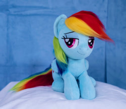 Size: 1098x948 | Tagged: safe, artist:buttercupbabyppg, imported from derpibooru, rainbow dash, pegasus, pony, female, folded wings, irl, lying down, mare, photo, plushie, prone, smiling, solo, wings