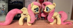 Size: 2048x806 | Tagged: safe, artist:rtryart, imported from derpibooru, fluttershy, pegasus, pony, duo, female, folded wings, irl, mare, photo, plushie, smiling, standing, wings