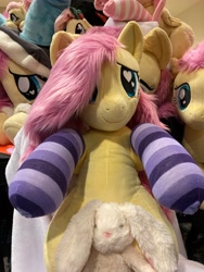 Size: 3024x4032 | Tagged: safe, artist:calusariac, artist:qtpony, imported from derpibooru, fluttershy, pegasus, pony, rabbit, animal, blanket, clothes, cute, everfree northwest, everfree northwest 2024, heart, heart eyes, hoodie, irl, multeity, photo, plushie, shyabetes, smiling, socks, striped socks, wingding eyes