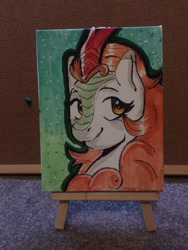 Size: 1536x2048 | Tagged: safe, artist:ratbytez, imported from derpibooru, autumn blaze, kirin, easel, horn, kirin horn, photo, smiling, solo, traditional art, watercolor painting