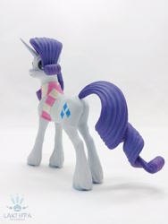 Size: 1620x2160 | Tagged: safe, alternate angle, alternate version, artist:lakterra, imported from derpibooru, rarity, pony, unicorn, butt, clothes, craft, female, figurine, horn, irl, mare, photo, plot, polymer clay, scarf, signature, simple background, smiling, solo, striped scarf, tail, unshorn fetlocks, white background