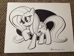 Size: 1024x768 | Tagged: safe, artist:thom zahler, imported from derpibooru, fluttershy, pegasus, pony, 2014, black and white, commission, female, folded wings, grayscale, heroescon, heroescon 2014, mare, monochrome, photo, raised hoof, smiling, solo, tail, traditional art, wings